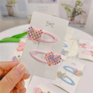 Close-up of pink rhinestone heart hair clips set on a white card display
