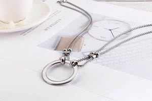 Close-up of a stylish silver round pendant necklace on a minimalist lifestyle magazine background