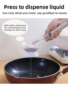 Macro view of soap dispensing dish brush with long handle cleaning a black frying pan