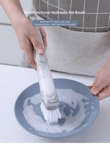 Close-up of long handle dish brush cleaning a plate with soap foam in kitchen