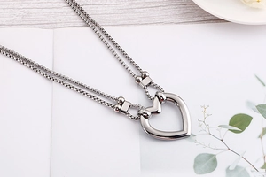 Detailed macro view of a silver double heart pendant necklace with a box chain on a desk