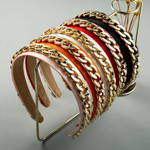Close-up of five colorful flower headbands featuring a bold golden chain link top detail