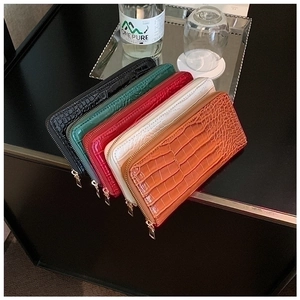 Detail view of five luxury crocodile-patterned long zip wallets in assorted colors