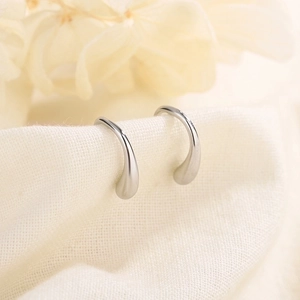 Elegant S925 silver teardrop earrings on a soft textured fabric with floral accents