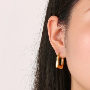 Close-up of elegant gold geometric U-shaped earrings on a model with a high-polish finish