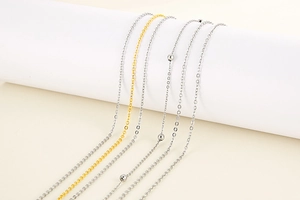 Detail of layered gold and silver stainless steel chains on minimalist white props