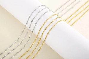 Macro shot of gold and silver layered stainless steel chains on white pedestal