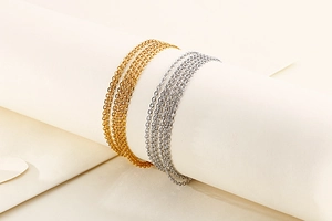 Detailed close-up of gold and silver stainless steel O-link chains on white stand