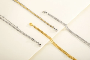Detail of layered gold and silver stainless steel chains with lobster clasp and beads