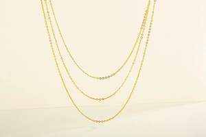Close-up of three golden minimalist stainless steel O-chains with polished metallic finish