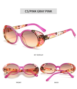 Detail view of oval sunglasses in pink floral frames with gradient amber lenses