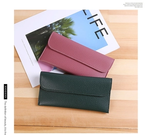 Flat lay of pink and dark green lychee textured leather wallets for women on wood