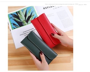 Close-up of red and green lychee pattern leather long wallets held over a magazine