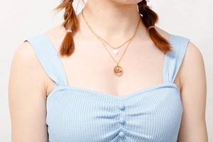 Detail of double-layer gold titanium steel necklace with Mom pendant on a model