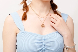 Detailed view of layered gold necklace with Mom pendant worn by model on white background
