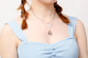 Detail of silver double-layered Mom pendant necklace worn on a model's neck