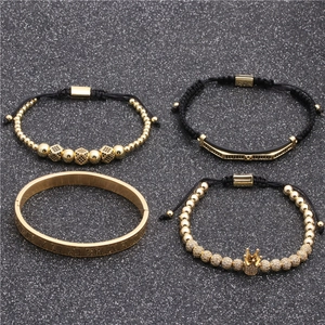 Dettaglio di quattro bracciali da uomo con ciondoli corona dorati e incisioni