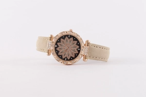 Close-up of rose gold starry watch with black lotus dial and beige suede leather strap