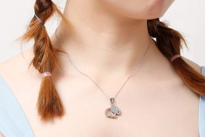 Close-up of minimalist silver elephant pendant necklace with small crystal on model