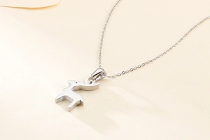 Dettaglio della collana con ciondolo a silhouette di cervo argento su fondo beige