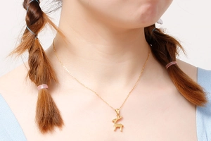 Dettaglio di una collana con ciondolo a forma di cervo dorato indossata da una modella