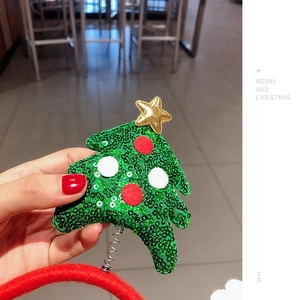 Detail of a green sequin Christmas tree headband with golden star and red spring