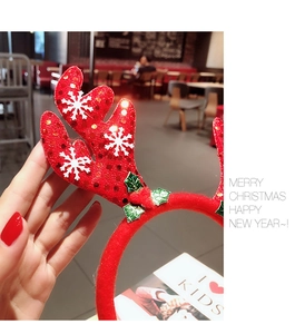 Detailed close-up of red sequin reindeer antlers headband with festive holly leaf decor