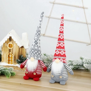 Pair of plush Christmas gnomes with snowflake hats and long beards on a snowy wood table