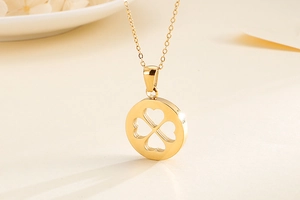 Détail d'un collier doré avec pendentif circulaire au motif trèfle à quatre feuilles