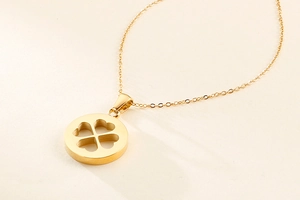 Détail d'un collier trèfle doré avec pendentif circulaire évidé et fine chaîne en O