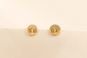 Detailed close-up of golden Tree of Life hollow stud earrings on a beige background
