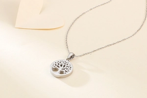 Close-up of silver hollow tree of life pendant with delicate chain on a soft background