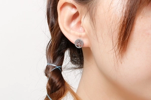 Close-up of silver Tree of Life earrings showing the hollow-out pattern on model ear