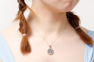 Macro detail of a silver Tree of Life pendant necklace worn by a fashion model