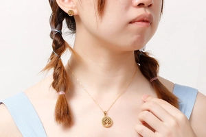 Model wearing golden Tree of Life hollow necklace and matching stud earrings set