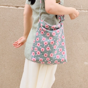 Detail of vintage corduroy tote bag with pink flower pattern worn as a crossbody