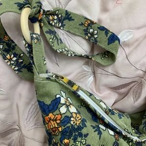 Detailed macro of green corduroy floral bag with metal zipper and wooden ring strap joint