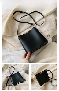 Detail of matte black leather bucket bag with elegant gold metal hardware bar