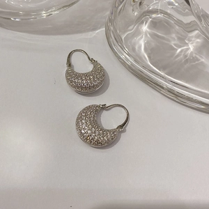 Macro shot of silver crescent hoop earrings featuring full pavé-set sparkling zircon stones