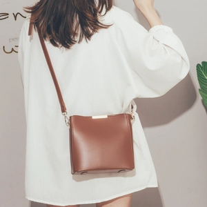 Detailed back view of a minimalist brown leather bucket bag with slim shoulder strap