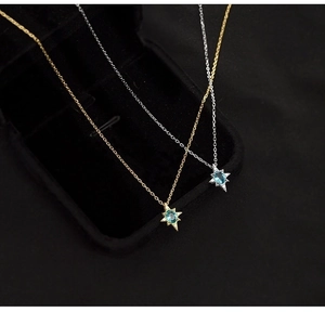 Detailed macro shot of an eight-pointed star pendant with blue gemstone in a black jewelry box