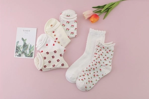 Flat lay of cotton women socks with cherry and heart patterns on a soft pink background