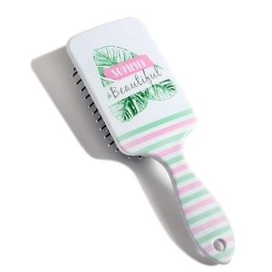 Detail of white plastic hairbrush with green tropical leaves and pink stripe pattern