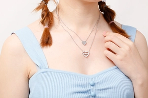 Close-up of double-layer silver heart necklace featuring solid and LOVE engraved pendants