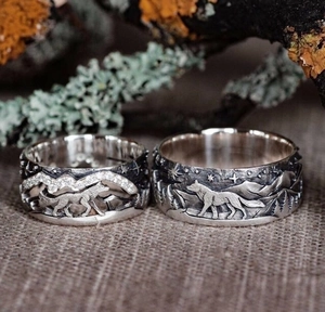 Detail of vintage wolf rings with mountain carving on rustic mossy wood background