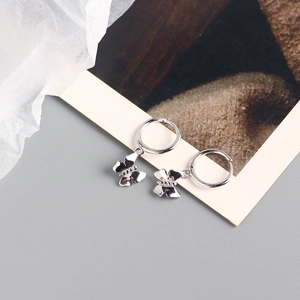 Close-up of minimalist silver butterfly hoop earrings on a decorative artistic card