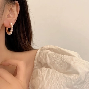 Elegant gold hoop earrings with high-luster pearls worn by a model in a minimalist setting