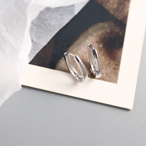 Close-up of minimalist S925 sterling silver U-shaped stud earrings on a paper background