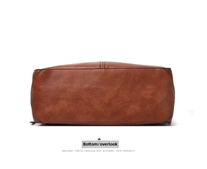 Detailed view of the brown leather tote bag bottom showing stitch and texture
