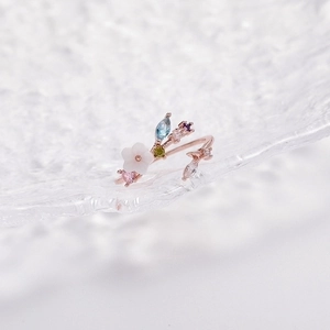 Macro detail of rose gold flower ring with colorful crystals and shell petal